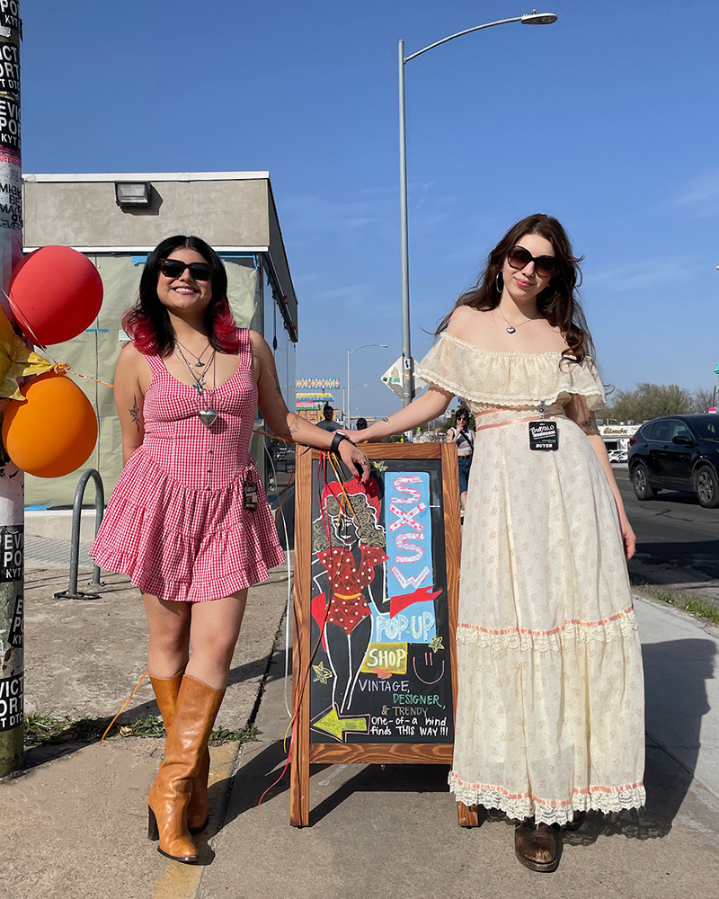 Two women stand in the sun wearing vintage dresses and brown boots